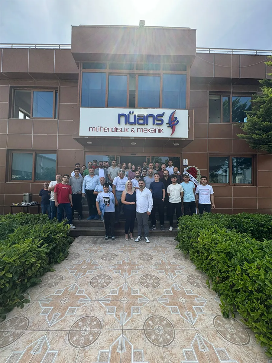 Nüans merkez ofisinin önünde toplanmış çalışanlar; bina cephesinde firma tabelası.
